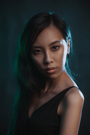 Young asian woman in black dress at motion in studio