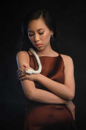 Asian woman with white artificial snakeの写真素材