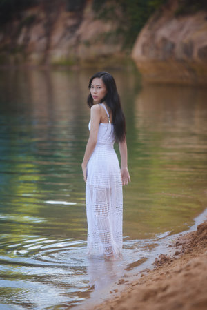 Young asian woman in white dress in pond, summer natureの写真素材