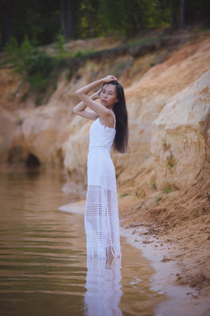 Young asian woman in white dress in pond, summer natureの写真素材