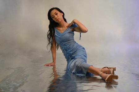 Young asian woman in blue evening dress posing at studioの写真素材