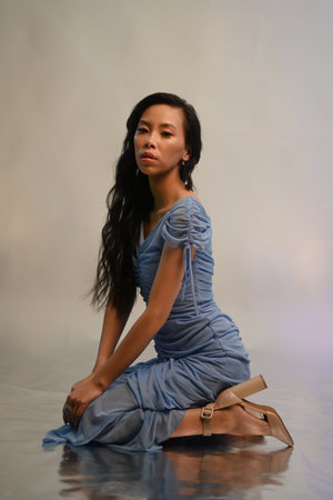 Young asian woman in blue evening dress posing at studioの写真素材
