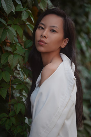 Portrait of young asian woman in leaves outdoorsの写真素材