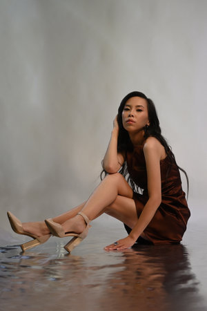 Young asian woman in brown dress sitting on floorの写真素材