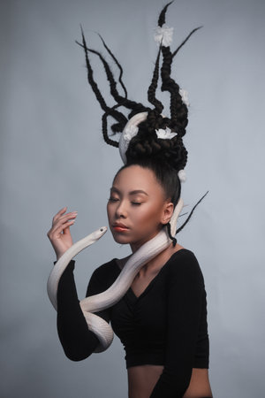 Studio portrait of young asian woman with white snakeの写真素材