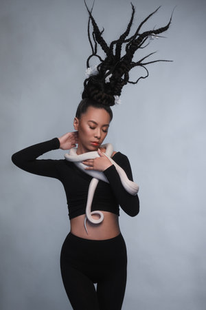 Studio portrait of young asian woman with white snakeの写真素材
