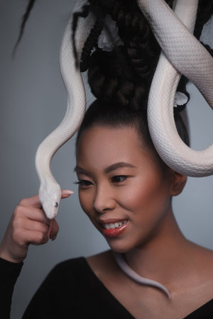 Studio portrait of young asian woman with white snakeの写真素材