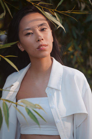 Portrait of young asian woman in leaves outdoorsの写真素材