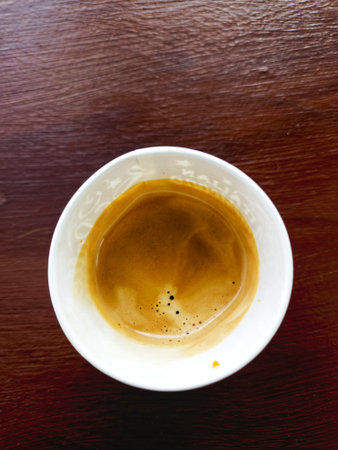 a glass of coffee stands on a wooden table.
