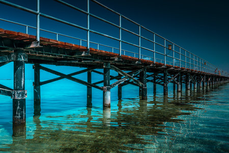Wooden pier in the sea with blue sky background. Long exposure