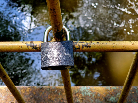 Padlock on a rusty bridge over the river, close-up