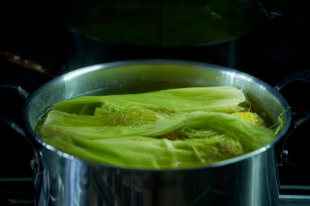 boiling sweet corn in a pot on the stove in the kitchen