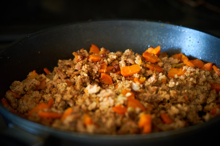 Fried minced meat with vegetables in a frying pan in the kitchen