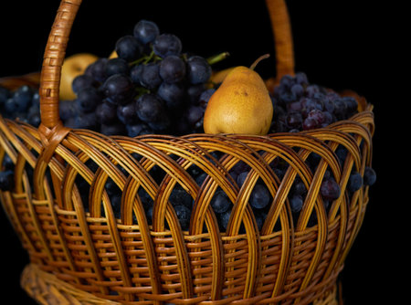 Wicker basket full of grapes and pears isolated on black backgroundの写真素材