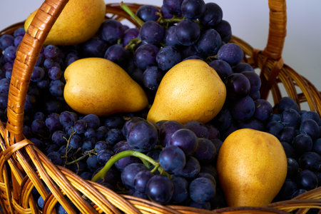Basket of grapes and pears on a white background close-upの写真素材