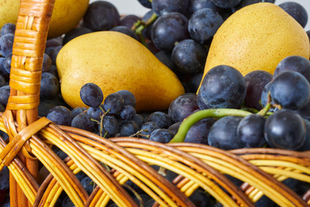 Basket with grapes and pears on a white background close upの写真素材