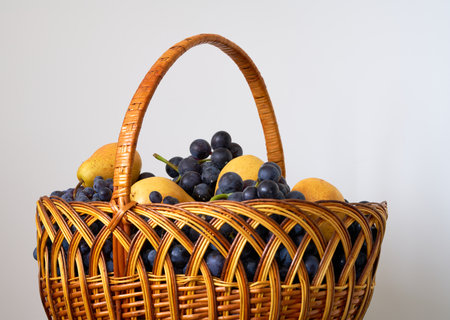 Wicker basket full of fresh fruits on a white background. Studio shot.の写真素材