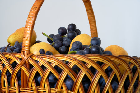 Wicker basket with fresh fruits on a white background, close-upの写真素材