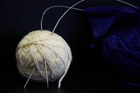 A ball of yarn and knitting needles on a dark background close upの写真素材