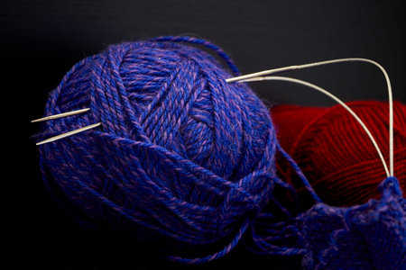 Ball of yarn and knitting needles on a black background. Close up.