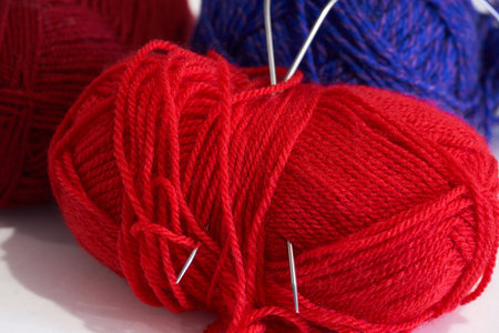 Red and blue skeins of yarn for knitting on a white background