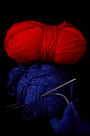 Ball of yarn with knitting needles on a black background. Studio shot.