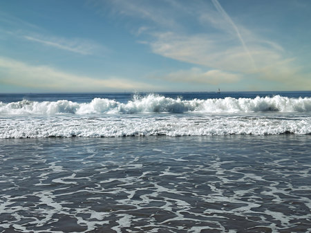 Seascape with waves breaking on the shore, blue sky and white clouds