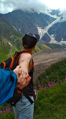 Guy holds girl's hand in the mountainsの写真素材