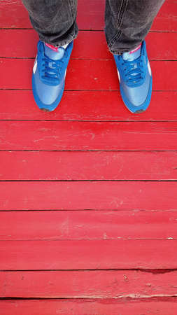 feet in blue sneakers on a red background
