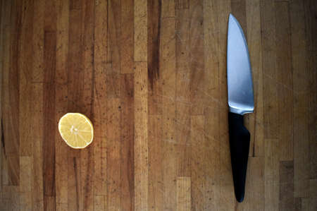 half a lemon and a knife on a wooden tableの写真素材