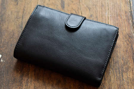 black leather wallet on a light wooden background