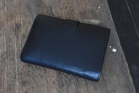 black leather wallet on a light wooden background