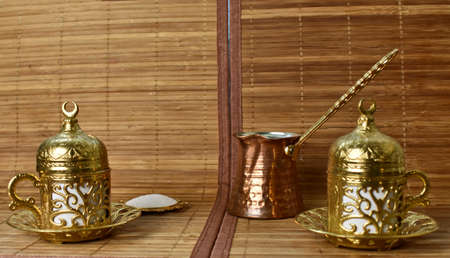 gold cups and Turk for coffee on a light background