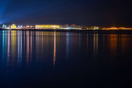 The illumination of the city is reflected in the water at nightの写真素材