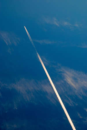 aircraft flying in the blue sky with clouds and a trace of itの写真素材