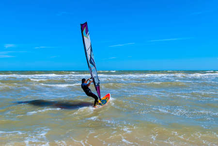 Windsurfing in stormy seas on the background of sky and clouds
