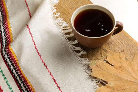 A cup of black tea on a table with a book and a shawlの写真素材
