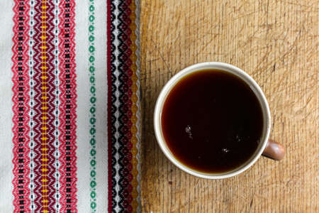 A cup of black tea on a table with a book and a shawlの写真素材