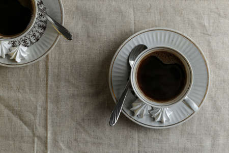 Coffee pot and cups with coffee on the table with a light linen tablecloth on a light background