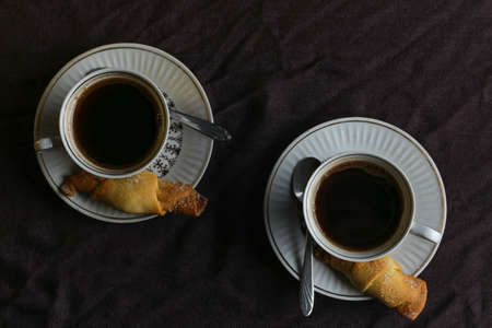 Ð¡ups with coffee on a table with a dark linen tablecloth with cookiesの写真素材