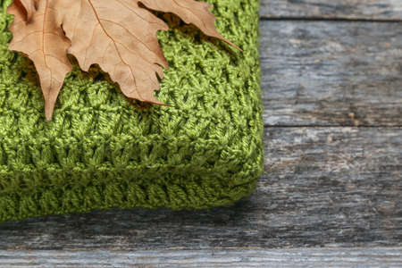 Knitted shawl with leaves on an old wooden tableの写真素材