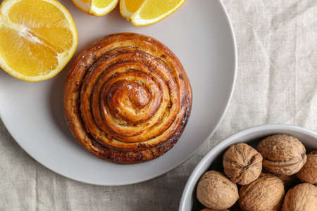 Cinnamon rolls on a gray plate on a bright table with a bowl of walnuts and orangeの写真素材