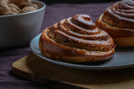 Cinnamon rolls on a gray plate on a dark table with a bowl of walnutsの写真素材