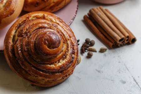 Cinnamon rolls on a pink plate on a bright table with a cup of milk and spicesの写真素材