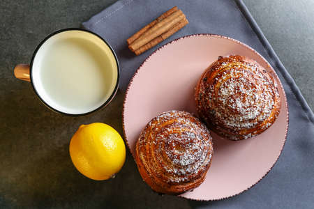 Cinnamon and coconut lemon buns on a pink plate on a gray table