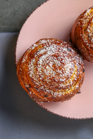 Cinnamon and coconut lemon buns on a pink plate on a gray tableの写真素材