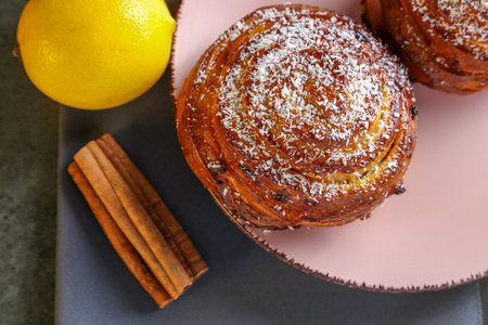 Cinnamon and coconut lemon buns on a pink plate on a gray tableの写真素材
