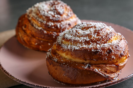 Cinnamon and coconut lemon buns on a pink plate on a gray tableの写真素材