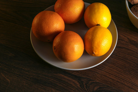 Lemons, oranges and walnuts in a gray bowl on a wooden tableの写真素材