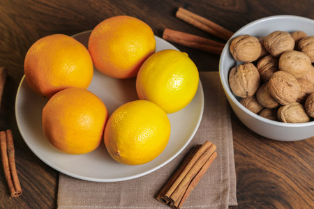 Lemons, oranges and walnuts in a gray bowl on a wooden tableの写真素材